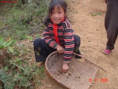 这小女孩自己家带来的撮箕破了，就蹲在路边临时补起撮箕来。农村孩子还是挺能干的。